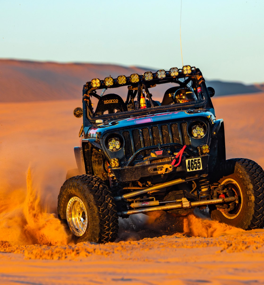 Jeep charging through sand dunes on SHOWA shocks