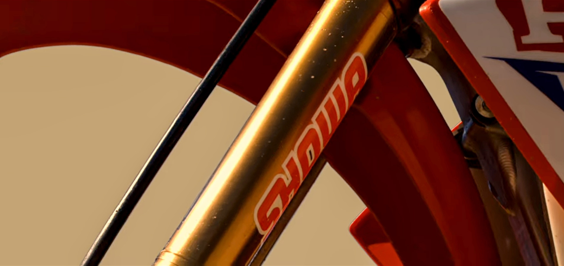Gold SHOWA fork leg on a motocross bike, close up
